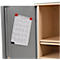 Open cabinet door with a drawing attached with red magnets. Next to it, the empty interior with shelves can be seen.
