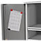 Grey cabinet door with a drawing attached with red magnets. Inside, a cabinet compartment with shelves can be seen.
