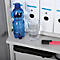 Blauwe waterfles en glas water naast ordners op een plank.