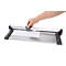 Person cutting paper with a paper cutter. Gray paper cutter with black base, white paper being cut.