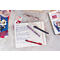 Gros plan sur un carnet, des stylos et des accessoires. Divers stylos reposent sur le carnet ouvert avec du texte.