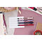 Quatre stylos roses, violets, bleus et rouges sur papier avec des lignes. Articles d'écriture à côté.