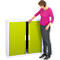 A woman opening a cabinet door. The cabinet is white with bright green doors. The woman is wearing a pink top and jeans.