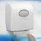 Dispensador de toallas de papel blanco en pared blanca. Manos sacando papel. Marca Kimberly-Clark.