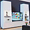 Modern white living room wall unit with TV, safe, and decoration. TV displays colorful blocks. Sculpture, books, and figure on the sides.