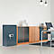 Blue-green safe, next to wooden cabinets. Desk with chair and lamps in the background.
