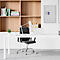 Schreibtisch mit Büchern, Lampe, Bürostuhl und Wandtresor. Bücherregal im Hintergrund. Helle, moderne Büroeinrichtung.