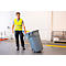 Een arbeider in een veiligheidsvest trekt een grijze afvalbak op wielen door een magazijn.