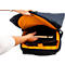 Une personne ouvre un sac à dos noir avec une doublure orange pour sortir un carnet et un ordinateur portable.