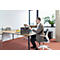 Un homme dans un bureau s'assoit et sort quelque chose d'un sac gris sur le bureau.