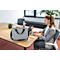Une femme tape sur un ordinateur portable, un sac gris et un bloc-notes sont sur la table.