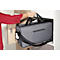 Une personne en haut rouge soulève un sac gris hors d'une armoire. Le sac a une bandoulière noire et une fermeture éclair.