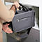 Personne tenant un sac d'ordinateur portable gris. Bras droit dans le placard. Bandoulière noire et grise.