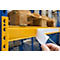 Hand houdt een wit etiket op een gele legplank. Boven, pallets. Magazijn op de achtergrond.