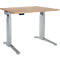 A height-adjustable desk with a light brown tabletop and silver legs. A control panel is attached to the desk.