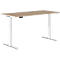 An adjustable height desk with a light wood top and white frame. The control is on the edge of the desk.