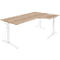 A light wood-colored corner desk with a white, height-adjustable frame. The tabletop is L-shaped.