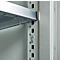 Close-up of a shelving system. A silver shelf is inserted into a holder, next to a series of holes and brackets.