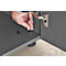Hand using an Allen key to screw a screw into a gray piece of furniture. A hinge can be seen in the background.