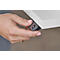 A hand presses a button. A finger operates a black button with a downward arrow on the underside of a white desk.