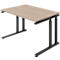 A height-adjustable desk with a light brown tabletop and black metal legs. It is positioned at a slight angle to show the construction.