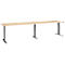 A long, rectangular, height-adjustable desk. The tabletop is light brown, the legs are dark gray.
