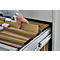 Hand in blue and white shirt reaching into a file cabinet with brown hanging files.