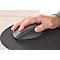 Eine Hand greift eine graue Computermaus, die auf einer schwarzen runden Unterlage liegt.
