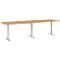 Long, rectangular, height-adjustable desk with a light wood look, gray legs and a gray base.