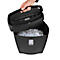 A person lifts the lid of a black paper shredder. The container is filled with shredded paper.