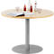 Round wooden table with drinks, magazine, grey leg and stand.