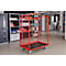 Red transport cart with grid, on wheels. In a warehouse, filled with goods.