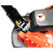 Detailed view of the mechanics of a lawnmower, with orange and black components. In the background a no-horn sign.