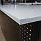 Gros plan d'un plateau de table avec une surface texturée. La table a un plateau gris et une base noire perforée.