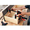 Une personne utilise des serre-joints pour assembler un tiroir. Les serre-joints sont noirs et rouges.