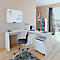 White corner desk with chair, laptop, and whiteboard. The room appears bright and minimalist.