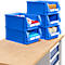 Blaue Kunststoffboxen auf einer Holzoberfläche mit Inhalten wie Kleidung, Geschenkpapier und Klebeband.