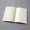 Un carnet ouvert avec des lignes sur une surface grise. Les pages crème sont vierges.