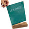 A hand holds a green sign with the word "LOUNGE". The sign stands on a wooden base.