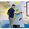 Ein junger Mann mit Brille und dunklem Poloshirt befestigt bunte Notizzettel an einem Whiteboard.
