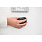 Une personne tient une souris noire. Un clavier et une bague en or au doigt sont sur la table.