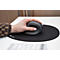 Main utilisant une souris verticale ergonomique grise sur un tapis de souris noir.
