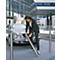 Business woman in suit installing a stainless steel bollard. A silver car is next to her.