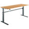 An adjustable-height desk with a light brown tabletop and gray metal legs. The height can be adjusted.