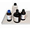 Four chemical bottles on a white tray. Two brown bottles and a light bottle with a handle. All have black lids.