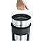 Hand holding a metal container with handle. The container is in a black plastic housing.