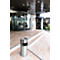 Stainless steel ashtray in front of an entrance hall. Revolving door, stairs and shiny ceiling in the background.