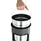 A hand holds a metal bucket, which is inserted into a dark, cylindrical container.