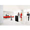 Several people are standing at high tables in a conference room. Red chairs are ready. Conference technology in the background.