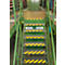 Green metal stairs with yellow and black warning markings in a warehouse. Two signs reading "Lagerstätte." Shelves in the background.